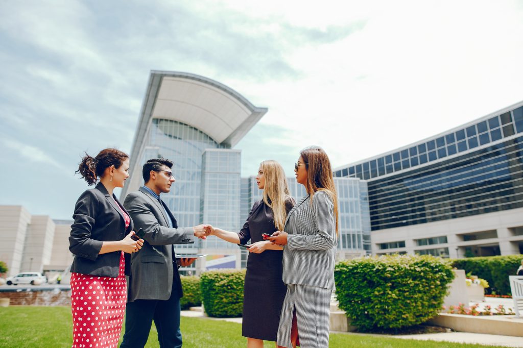 Two professionals shaking hands outdoors with commercial buildings behind them, representing joint venture real estate
